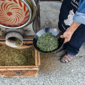 A person preparing green tea leaves using traditional methods in Kurashiki, Japan.