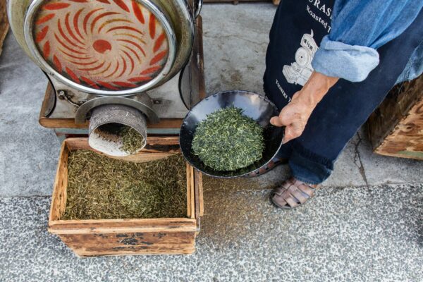 A person preparing green tea leaves using traditional methods in Kurashiki, Japan.