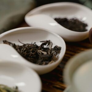 Porcelain dishes holding various loose tea leaves, highlighting traditional tea culture.