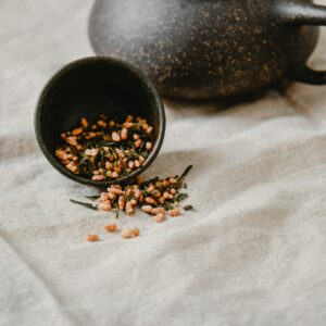 A rustic display of Genmaicha tea in a Japandi setting with a stone teapot.