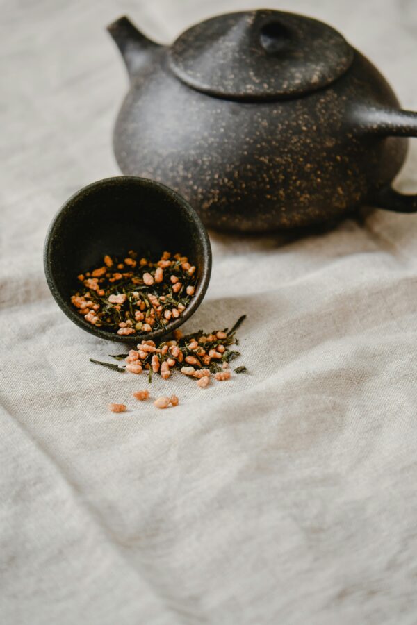 A rustic display of Genmaicha tea in a Japandi setting with a stone teapot.